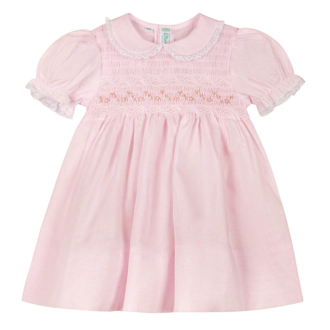 Pink baby dress with lace details on a white background