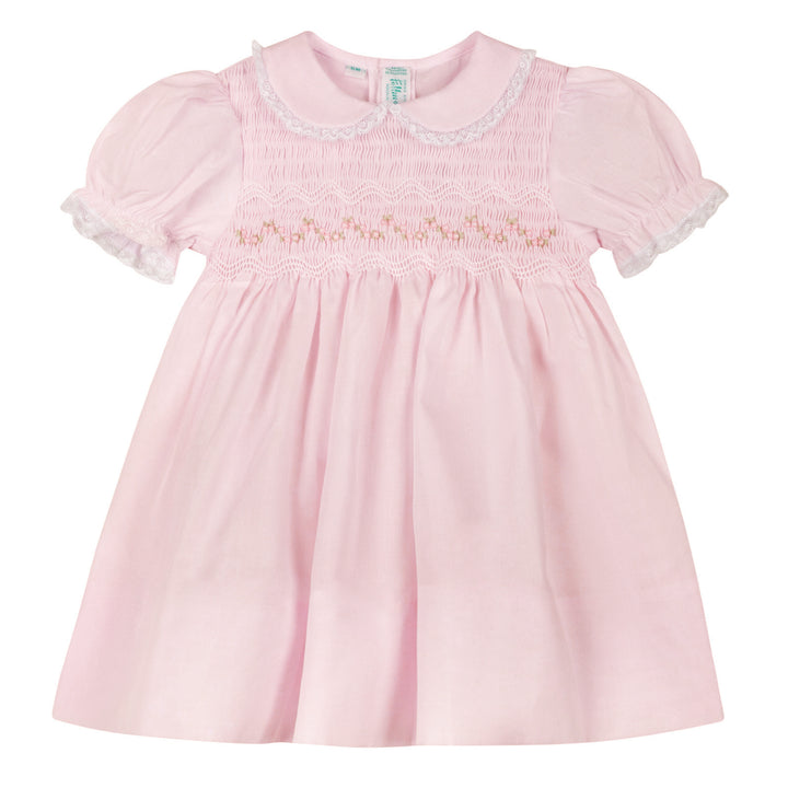 Pink baby dress with lace details on a white background