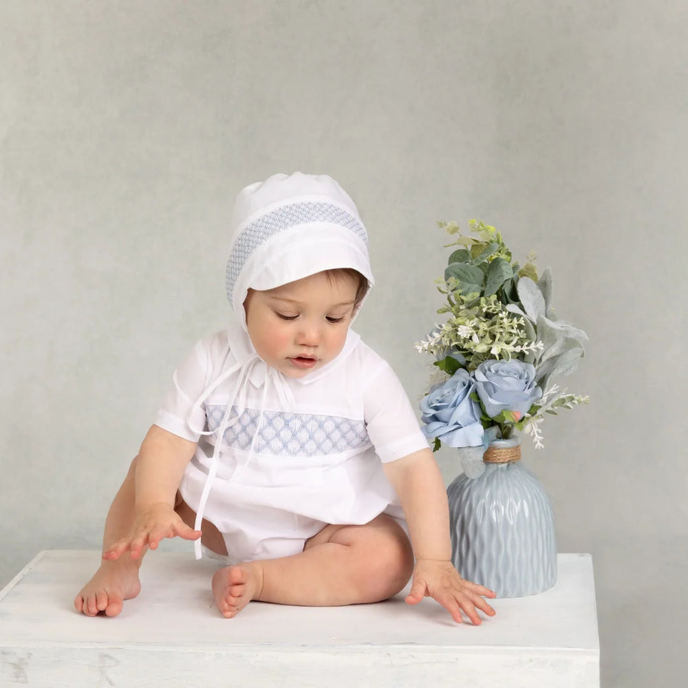 Baby sitting on a white surface with a neutral background