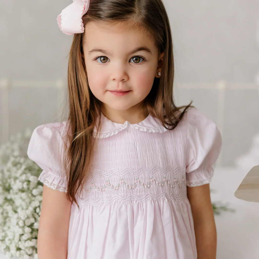 Young girl wearing a pink dress with a white background