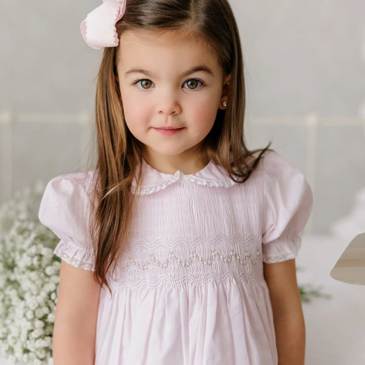 Young girl wearing a pink dress with a white background