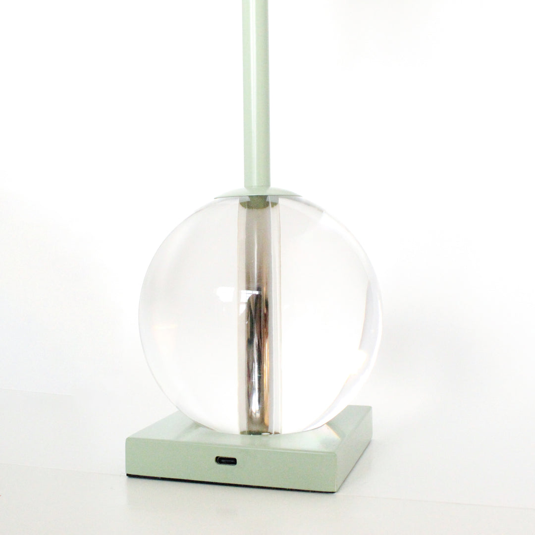 Modern pendant light with clear glass shade and green base on a white background