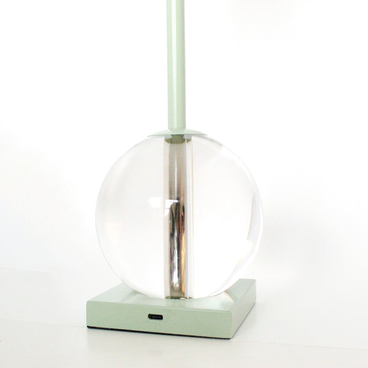 Modern pendant light with clear glass shade and green base on a white background