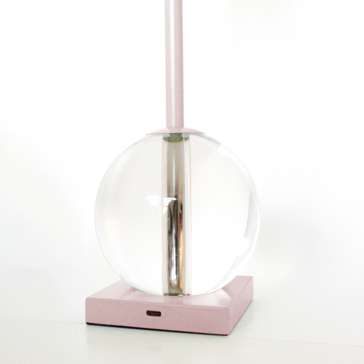Modern pendant light with clear glass shade and pink base on a white background