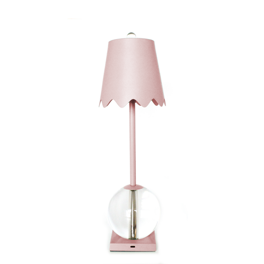 Pink table lamp with a scalloped shade on a white background