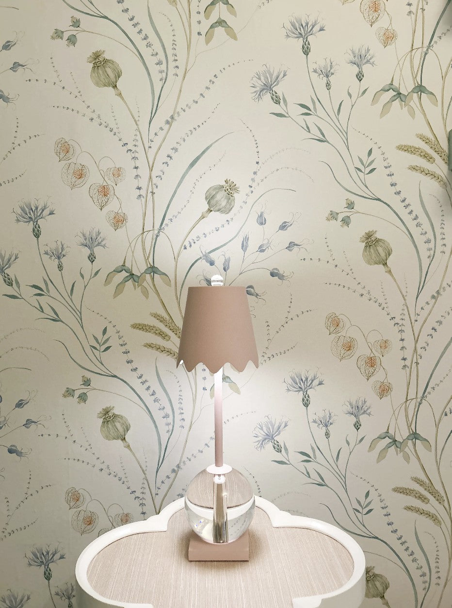 Decorative lamp on a table with floral wallpaper in the background
