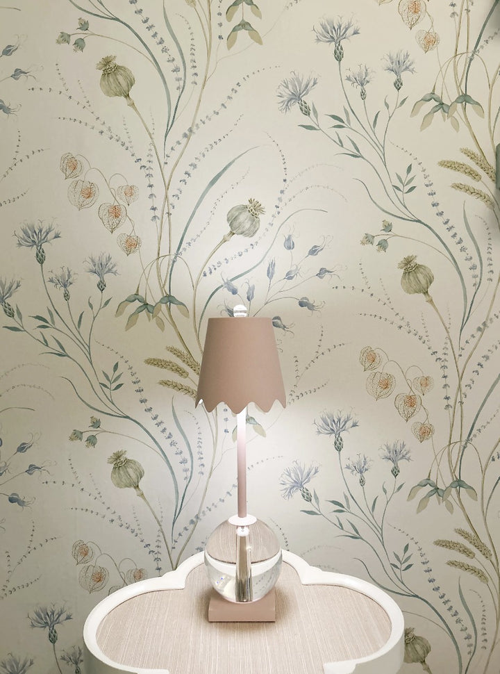 Decorative lamp on a table with floral wallpaper in the background