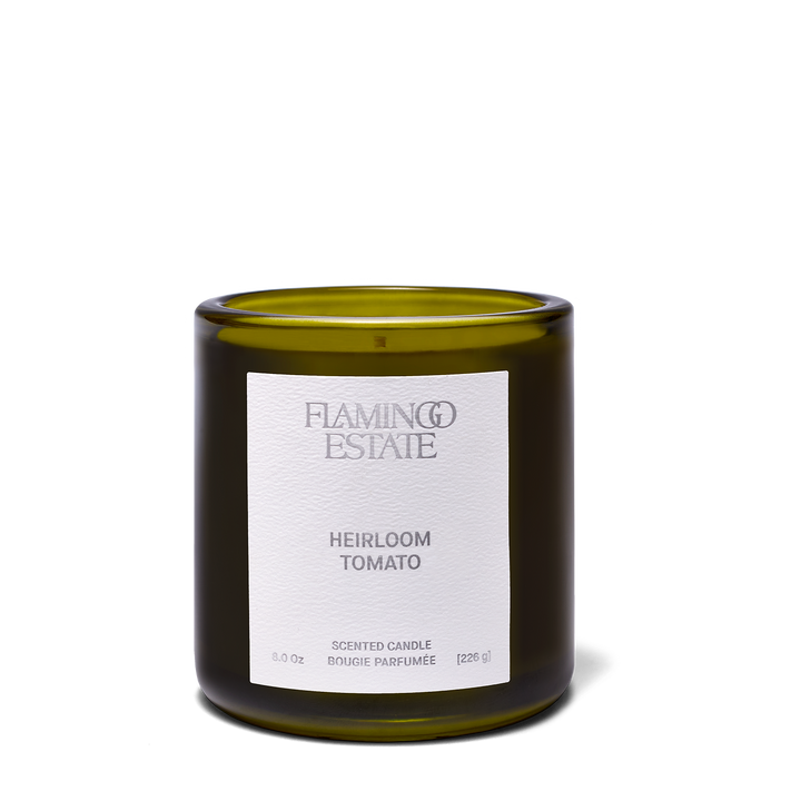 An amber glass candle jar with a white label reading 'FLAMING ESTATE' and 'SAPPHO FIG' on a clean white background.
