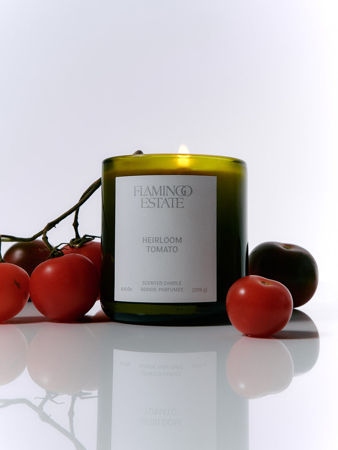 Haminco Estate Heirloom Tomato candle with tomatoes on a reflective surface
