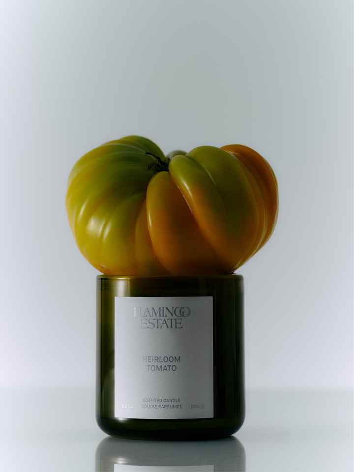 Candle in a container shaped like a heirloom tomato with 'Lampe Berger' branding on a white background