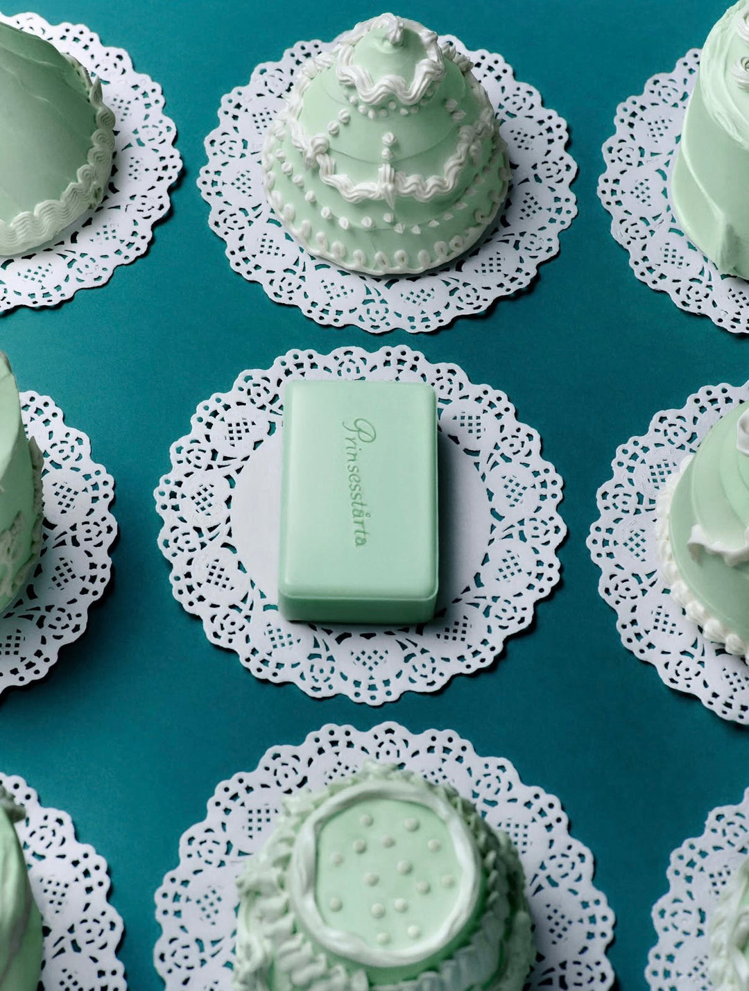 A mint green rectangular bar of soap with the brand name 'P. Rossetti' printed on it, displayed on a white lace doily over a teal background, surrounded by matching mint green decorative objects.