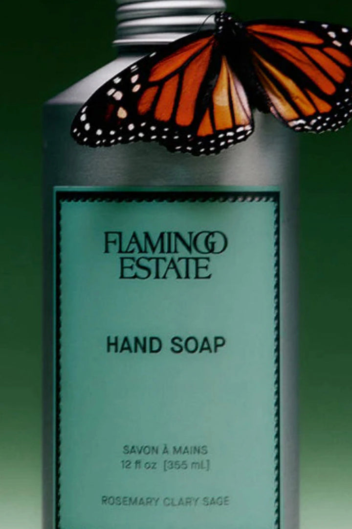 Flamingo Estate Hand Soap in a silver bottle with a mint green label, topped with a monarch butterfly against a dark green background.