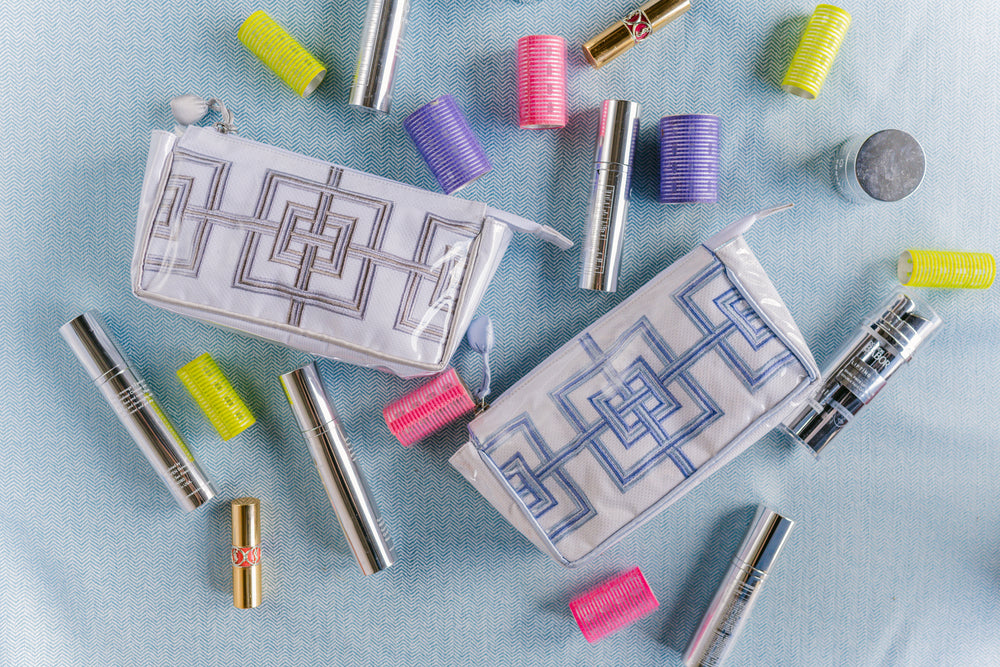 Makeup items including lipsticks and a pouch with geometric patterns on a light blue background