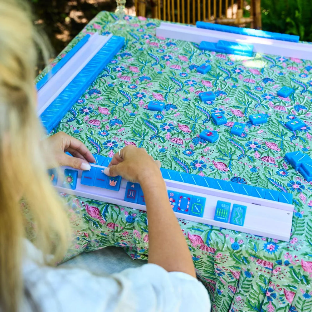 Person playing with a colorful board game on a floral-patterned table