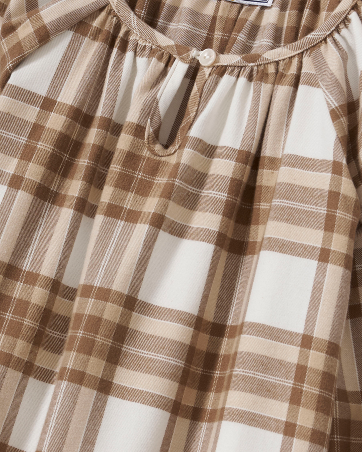 A child model shown from the back wearing a long-sleeve plaid nightgown in brown and cream, standing against a solid light beige background.