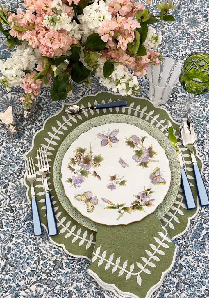 Table setting with floral-patterned plates and cutlery on a textured tablecloth.
