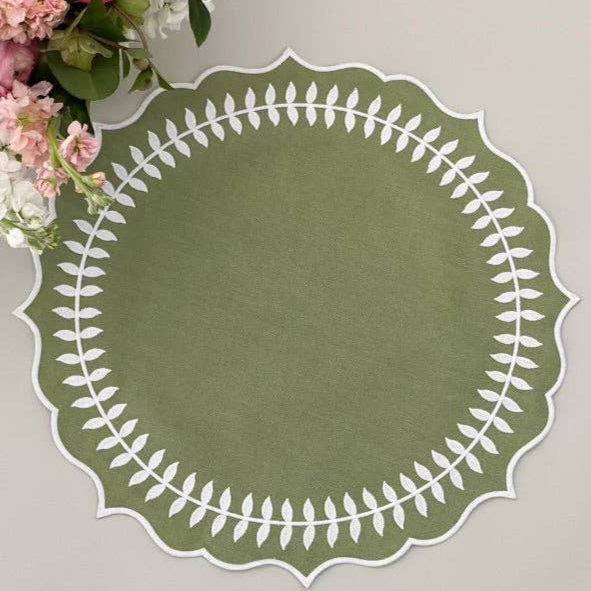 Green placemat with white leaf pattern next to a bouquet of pink and white flowers on a light gray background