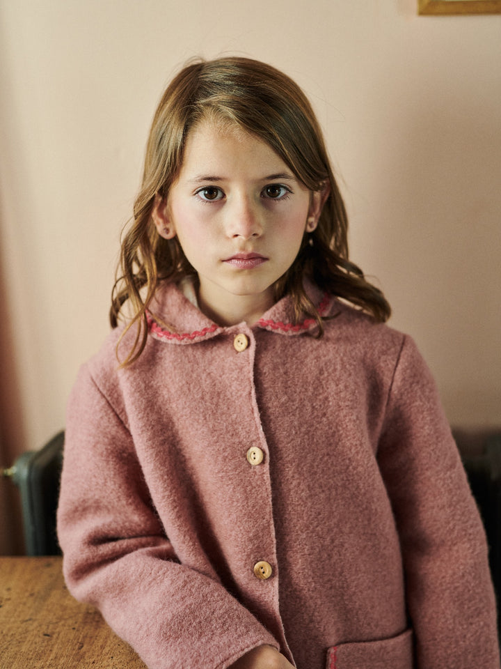 Young girl wearing a pink coat with a neutral background