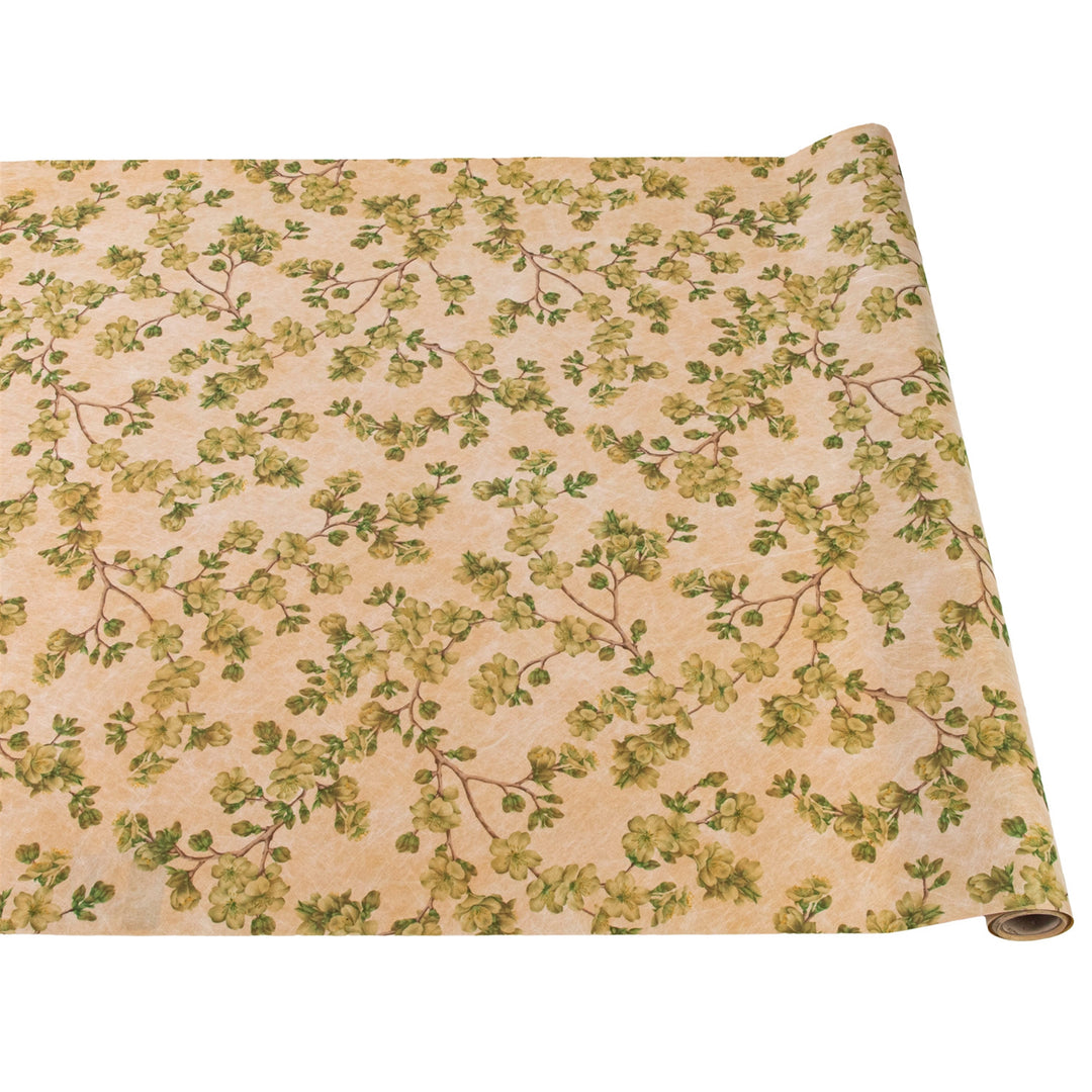 Roll of fabric with green floral pattern on beige background