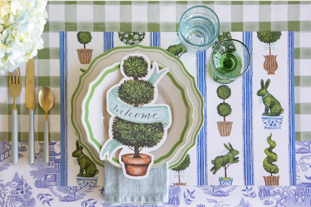 Decorative table setting with a 'Welcome' placemat on a checkered tablecloth.