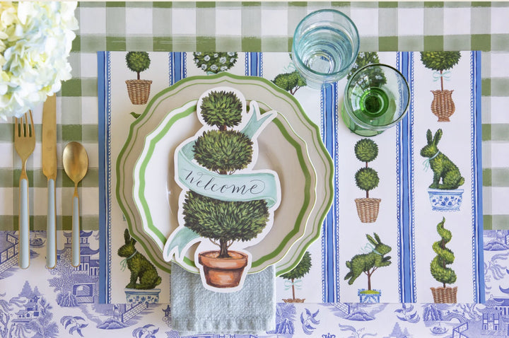 Decorative table setting with a 'Welcome' placemat on a checkered tablecloth.