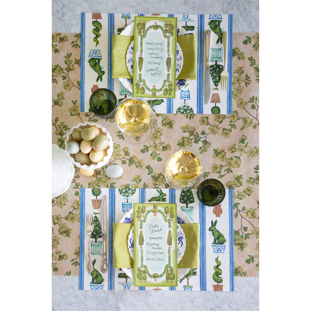 Decorative table setting with patterned placemats and tablecloth, featuring green and blue elements.
