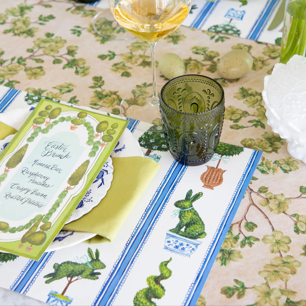 Easter-themed table setting with decorative placemats, glasses, and a menu.