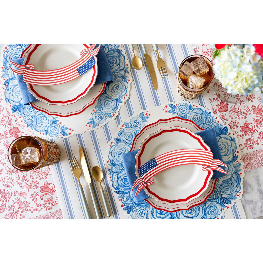 Table setting with red, white, and blue theme on a floral tablecloth.