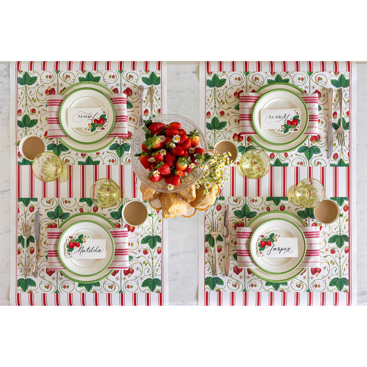Decorative table setting with place mats, plates, and a bowl of fruit on a white background.
