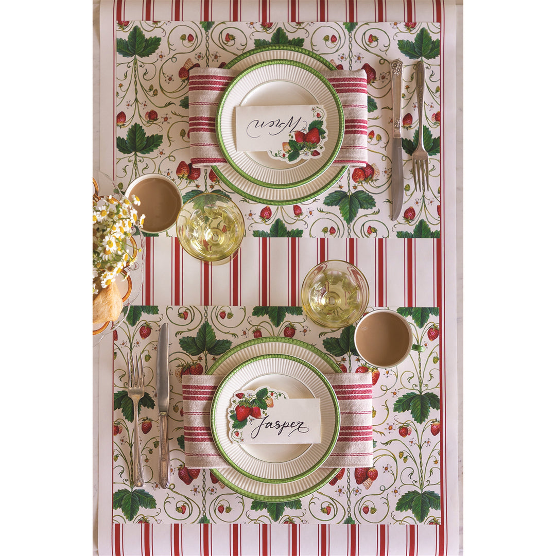 Decorative table setting with striped tablecloth, plates, and cutlery on a white background