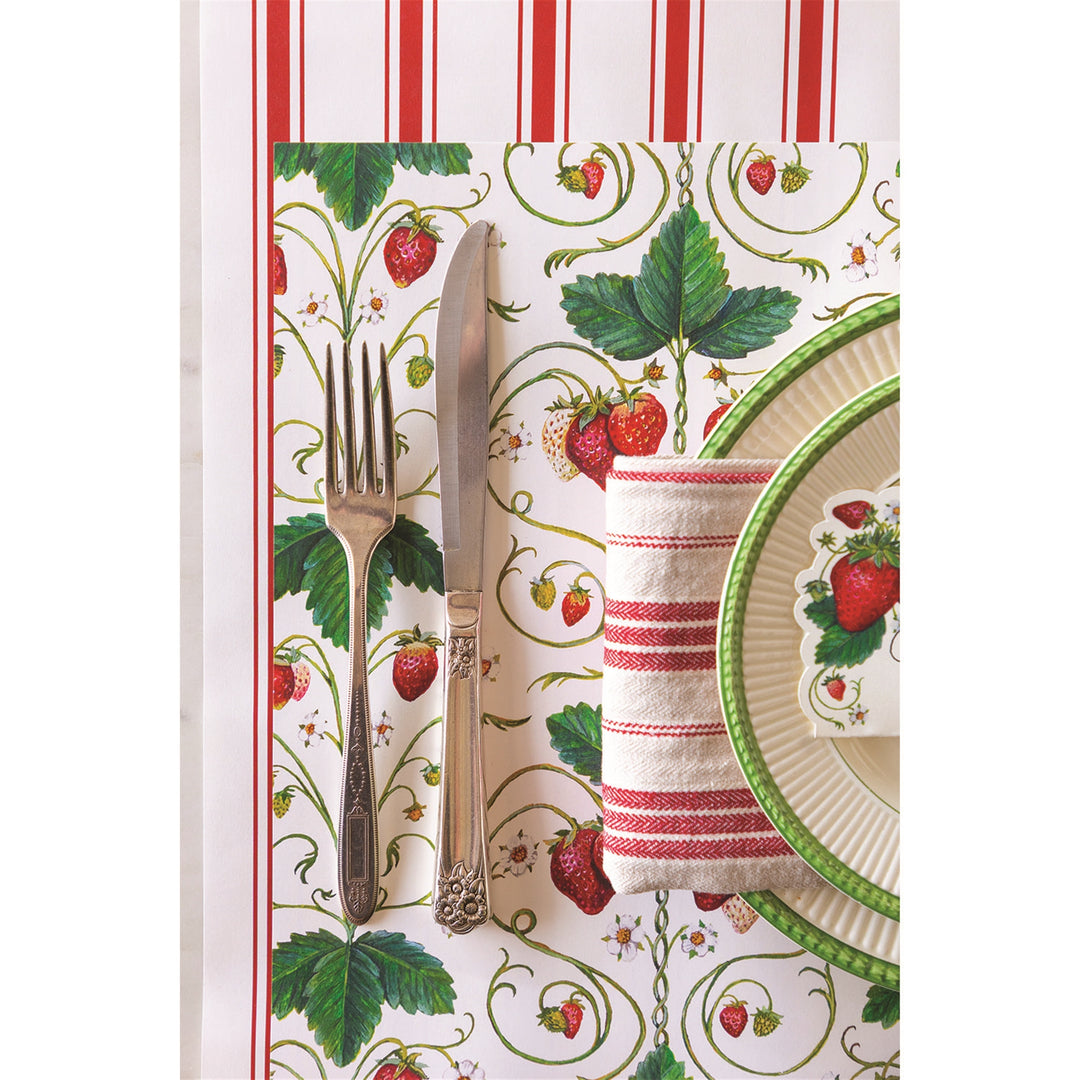 Placemat with strawberry design featuring cutlery and a napkin on a striped background