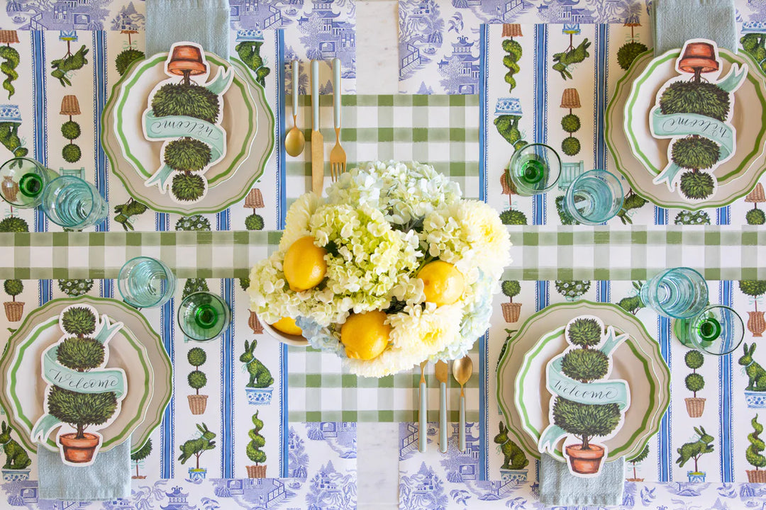 Decorative table setting with floral arrangement and plates on a patterned tablecloth.
