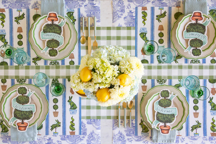 Decorative table setting with floral arrangement and plates on a patterned tablecloth.