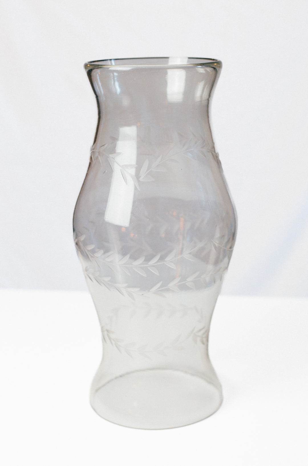 A clear glass vase with a flared rim and etched leaf patterns, shown on a plain white background.