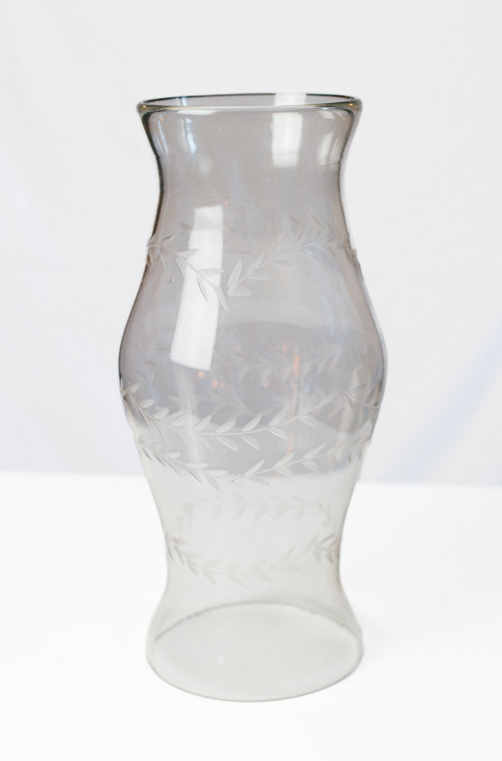A clear glass vase with a flared rim and etched leaf patterns, shown on a plain white background.
