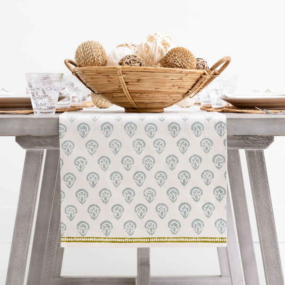 Table setting with a patterned tablecloth, basket, and glasses on a white background