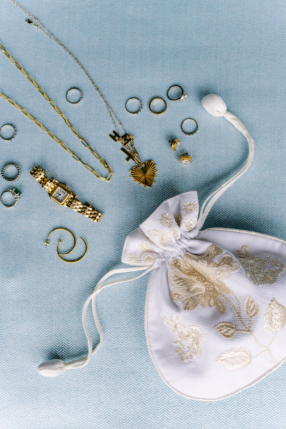 Jewelry set with a white embroidered pouch on a light blue background