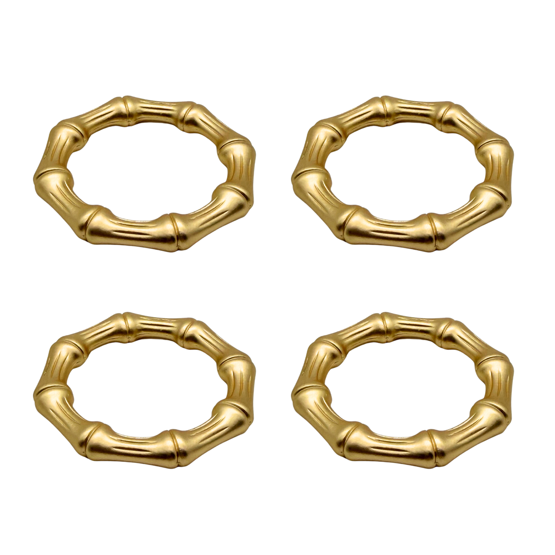 Four gold bamboo-style napkin rings on a white background
