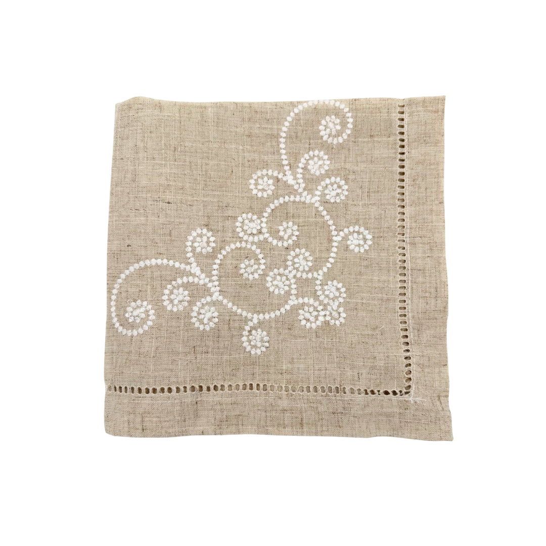 Beige napkin with white floral embroidery on a white background