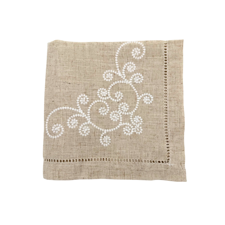 Beige napkin with white floral embroidery on a white background