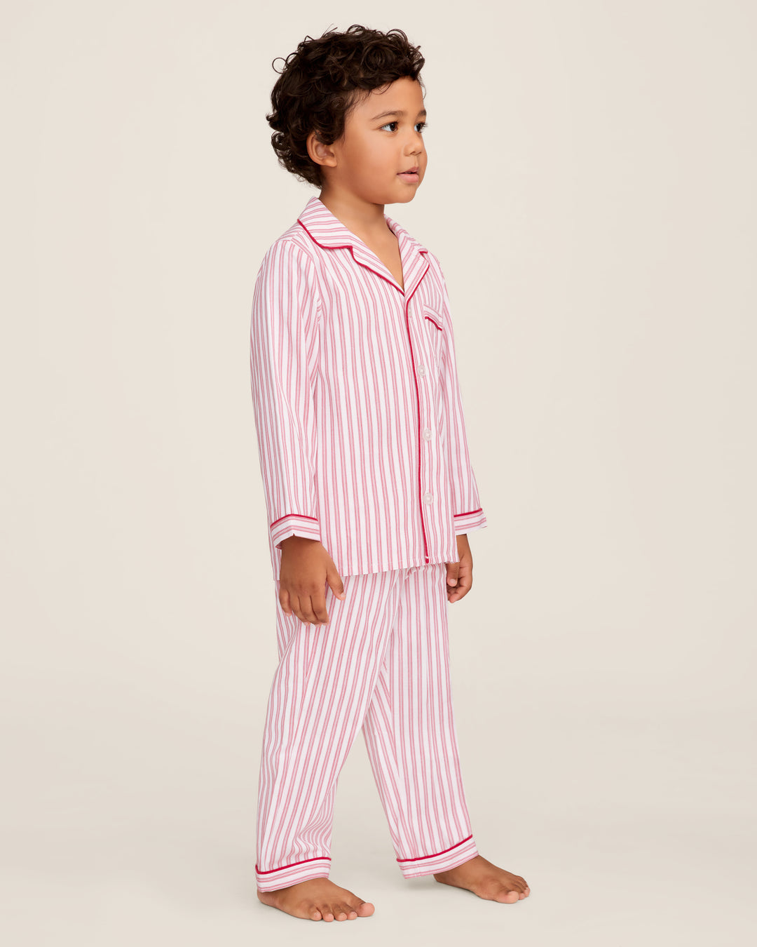 Child wearing red and white striped pajamas on a plain background