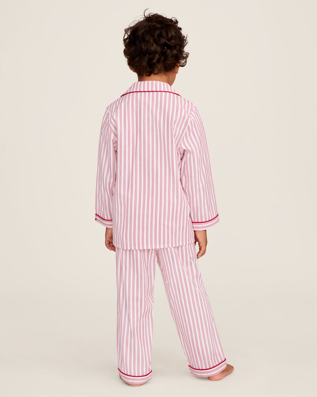 Child wearing red and white striped pajamas on a plain background