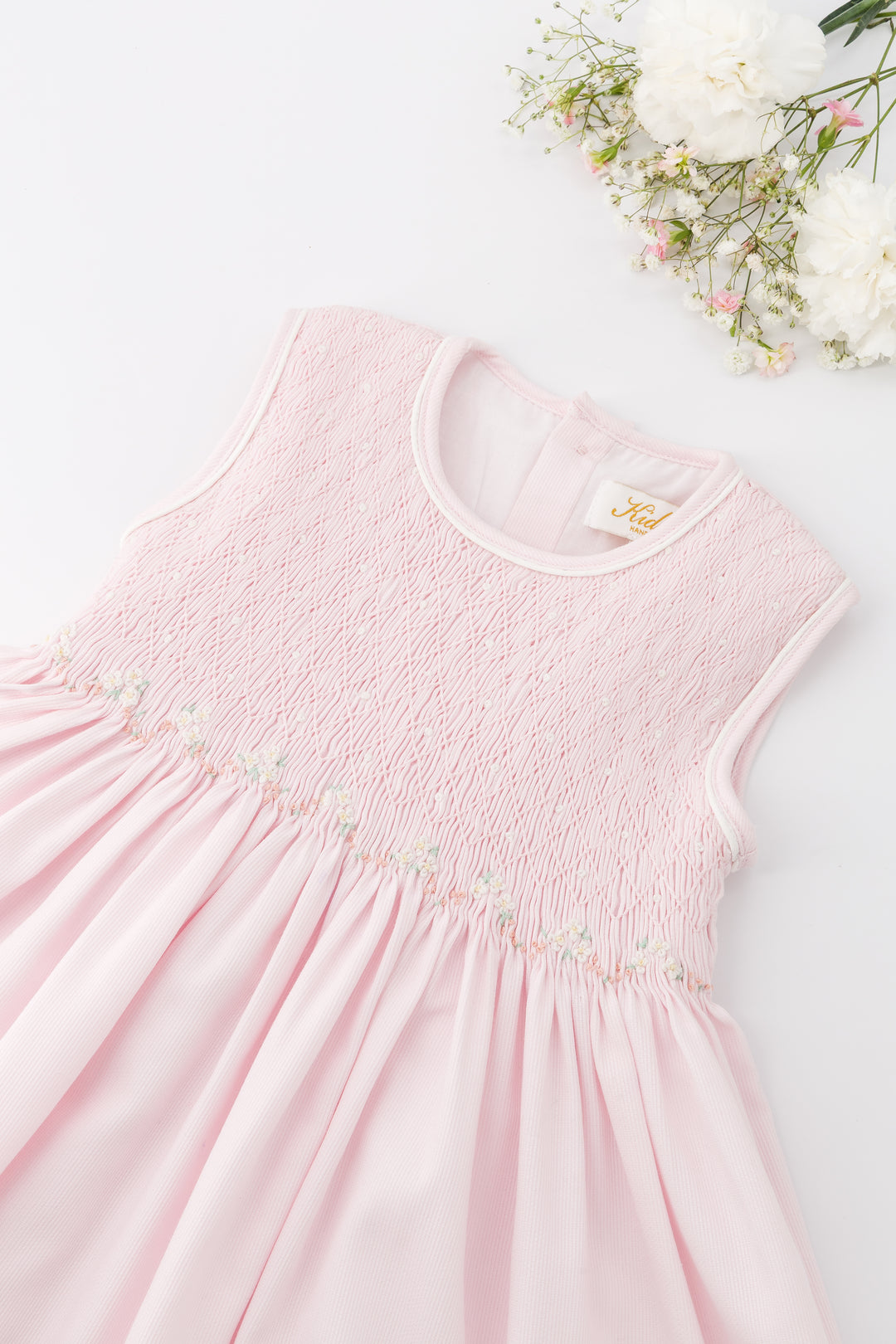 Pink dress with floral embroidery on a white background