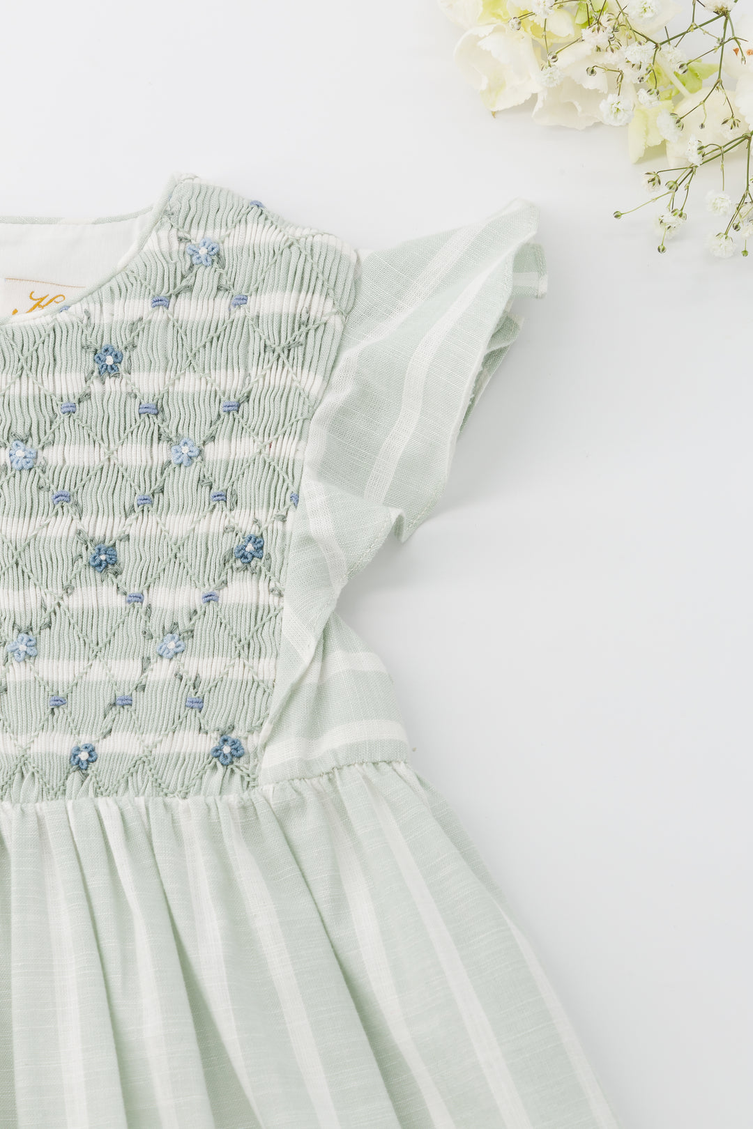 Light green dress with floral embroidery on a white background