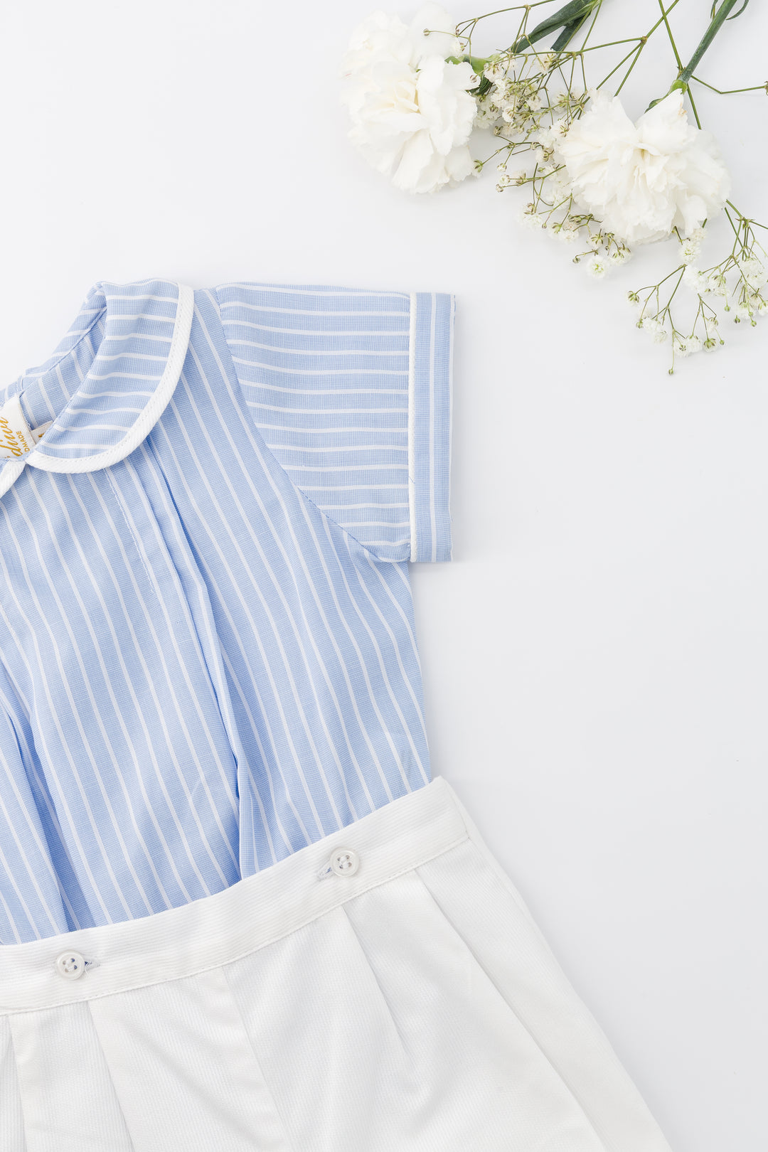 Blue and white striped shirt with white shorts on a light background