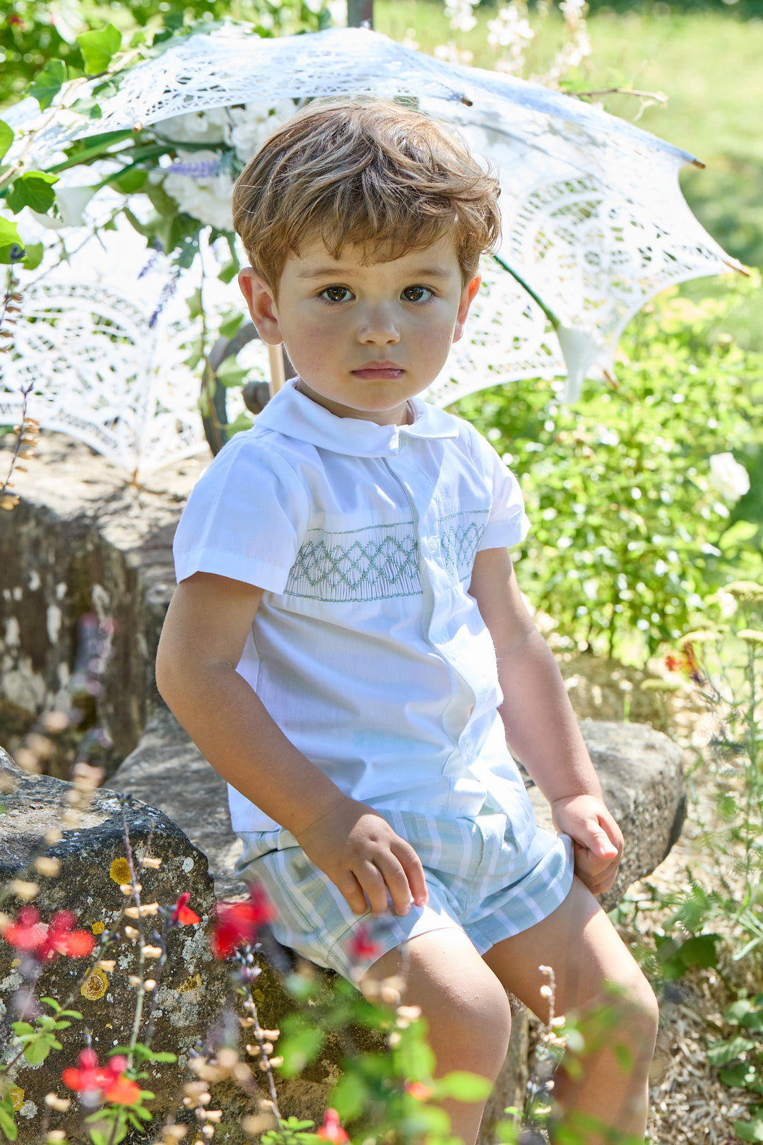 Toddler Boy wearing Smocked Outfit Sitting Outside with Parasol