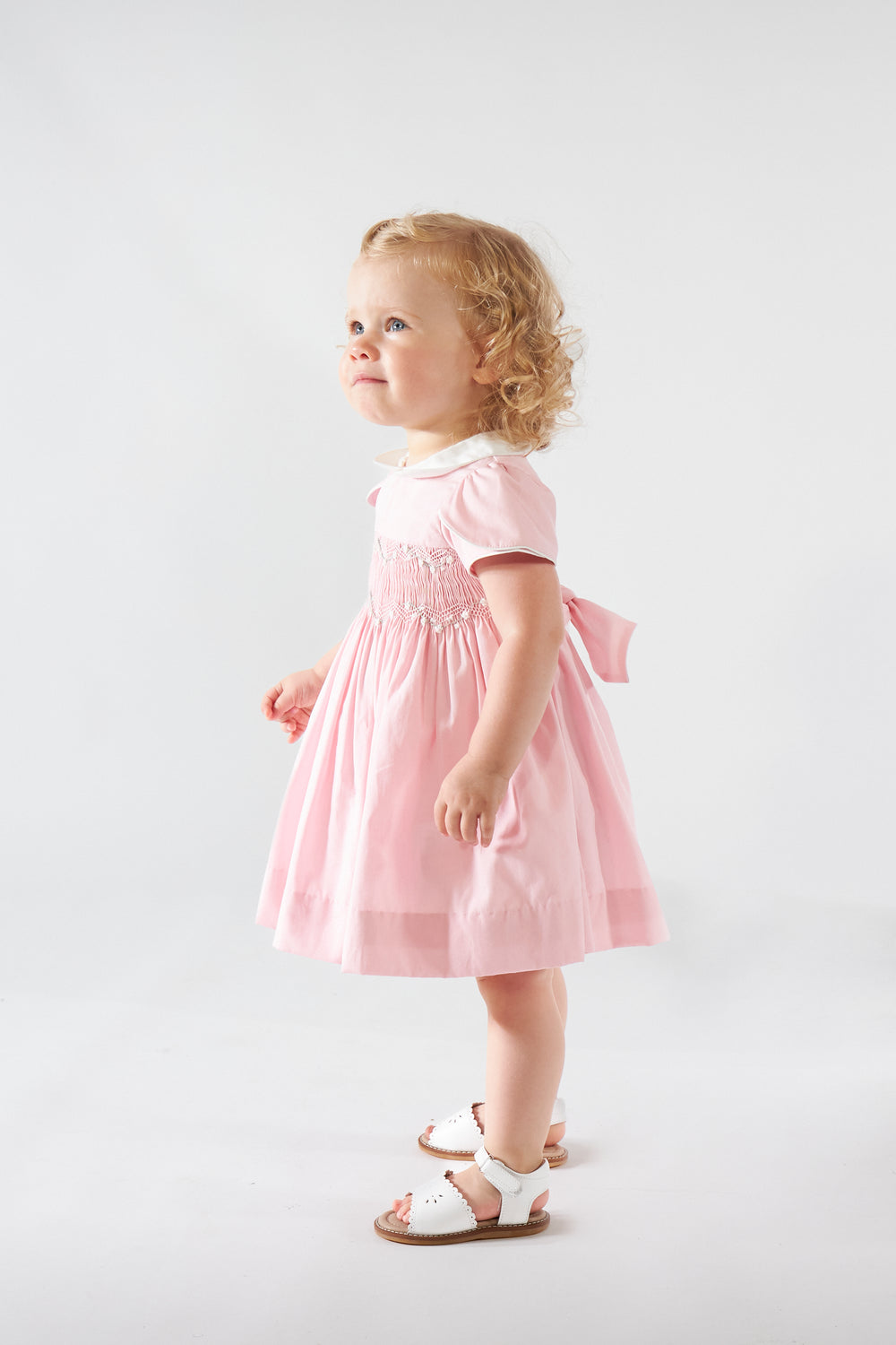 Young child wearing a pink dress on a white background