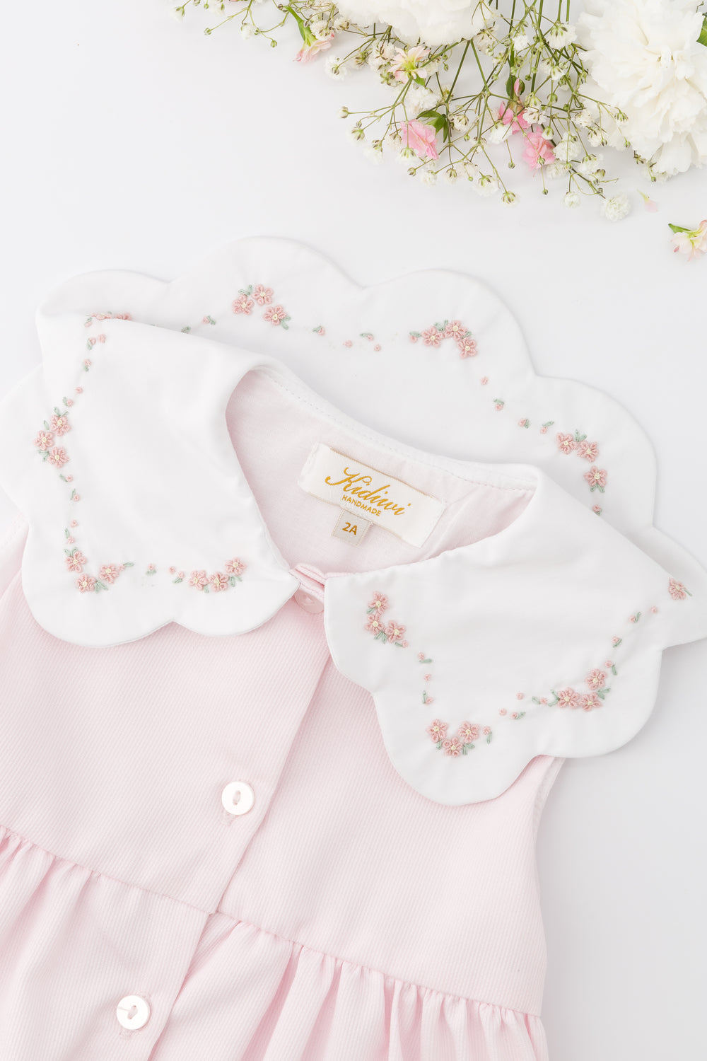 Close up of Pink Dress with embroidered Bib collar on white background with floral 