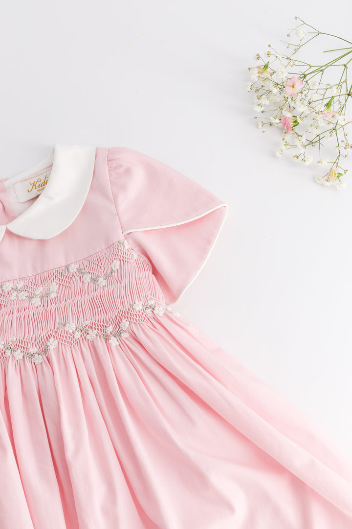 Pink dress with white collar and floral embroidery on a light background