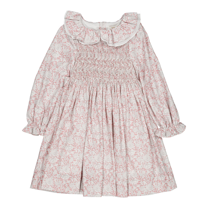 A long-sleeve baby dress with a pink floral toile pattern on a white background, featuring a smocked bodice, ruffled collar, and gathered sleeves.